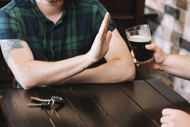 A person declining an alcoholic drink offered by a friend